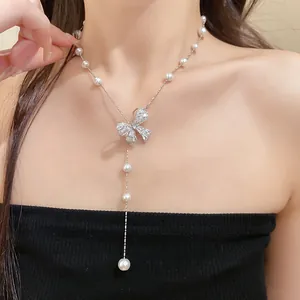 Close-up of elegant bow pendant necklace with zircon and pearls on clavicle chain.