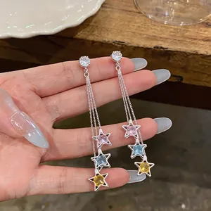 Detailed view of long star tassel earrings with colorful zircons and silver finish.