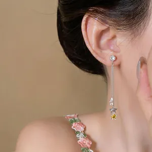 Detail view of elegant long tassel earrings featuring sparkling star pendants and zircons