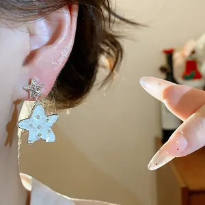 Close-up view of a silver needle star earring with rhinestones and mother-of-pearl