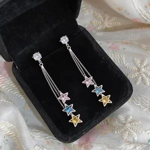 Detail view of long tassel earrings with colorful star-shaped zircons in a box.