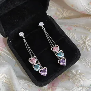 Detailed macro shot of long tassel earrings featuring pink, blue, and purple heart-shaped stones