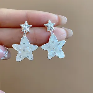 Close-up of elegant silver star earrings with mother-of-pearl inlay and sparkling rhinestones