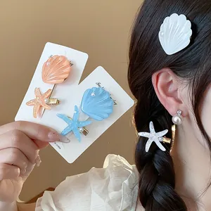 Close-up detail of resin starfish and seashell hair clips worn by model and on cards.