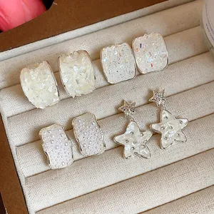 Dettaglio di quattro paia di eleganti orecchini a stella e geometrici in argento in un vassoio.