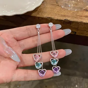 Detailed macro view of silver long tassel earrings featuring colorful crystal heart charms