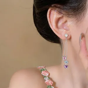 Close-up of elegant long tassel earrings with colorful heart-shaped zircons