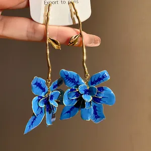 Vista macro dettagliata di orecchini a fiore in smalto blu con eleganti steli dorati
