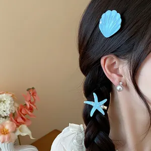 Detail of elegant blue resin starfish and shell hair clips worn on dark braided hair