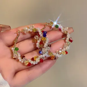 Detailed macro view of vibrant multicolored bead and pearl wrapped large gold hoop earrings
