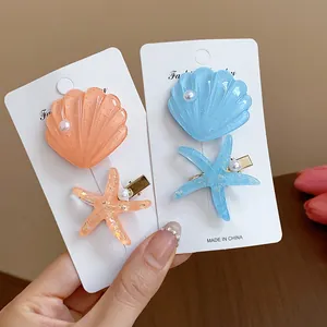 Set of two resin hair clips featuring starfish and seashell designs with pearl accents