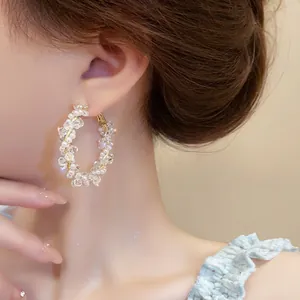 Close-up of elegant gold hoop earrings wrapped with white pearls and clear crystal beads