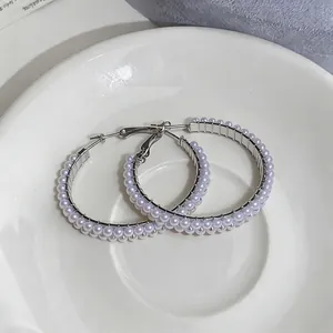 Elegant silver large hoop earrings with double-row white pearls on white ceramic plate