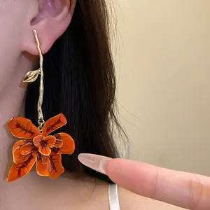 Primo piano dettagliato di un orecchino a fiore in smalto arancione con stelo oro