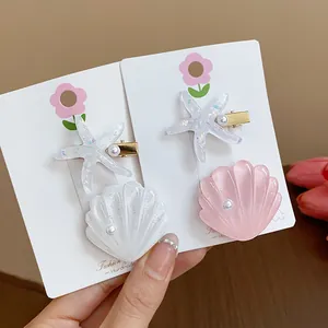 Detailed view of glittery resin starfish and seashell hair clips on white display cards