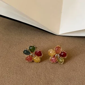 Dettaglio di squisiti orecchini a lobo a forma di fiore color gelatina con eleganti tocchi dorati