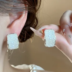 Dettaglio di eleganti orecchini color argento con texture a bolle di perle sull'orecchio