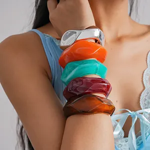 Detailed view of colorful chunky irregular geometric resin bangles on female model wrist
