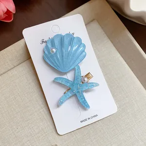 Close-up of blue resin shell and starfish hair clips with glitter and pearls
