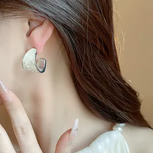 Dettaglio ravvicinato di eleganti orecchini a forma di C in stile coreano con inserto in madreperla