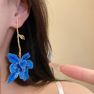 Primo piano dettagliato di orecchini pendenti a fiore in smalto blu vintage indossati da una modella