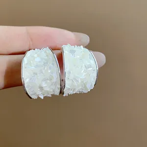 Macro dettagliata di orecchini a perno in argento con trama di vetro rotto bianco