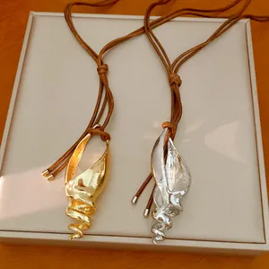 Primo piano dettagliato di due collane artistiche a conchiglia in finitura oro e argento