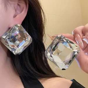Detailed close-up of oversized square crystal stud earrings with multifaceted cut