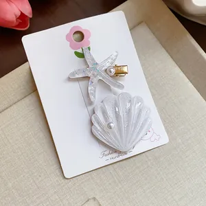 Close-up of sparkly resin starfish and seashell hair clips with elegant faux pearls