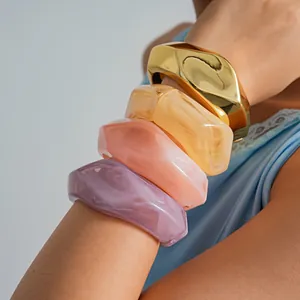 Detailed view of colorful irregular geometric resin and gold metallic bangles on a model