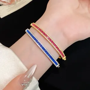 Detail view of vintage-style gold and silver bangles with red and blue cubic zirconia.