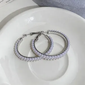Macro view of elegant silver hoop earrings decorated with double rows of white pearls