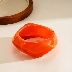 Close-up of a chunky orange resin geometric bangle with irregular fashion design