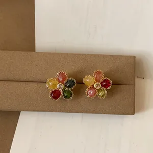 Dettaglio di orecchini a lobo a forma di fiore colorati con bordi dorati