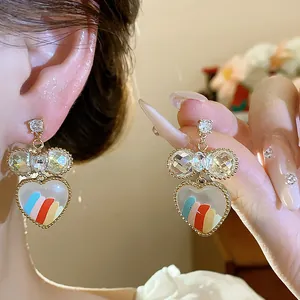 Vue rapprochée de boucles d'oreilles cœur en verre plaqué or 18 carats avec nœud diamant.