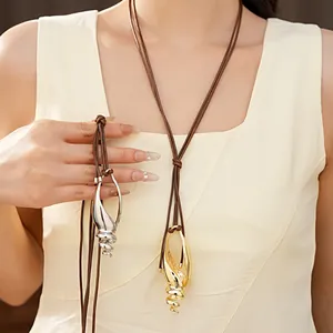 Dettaglio di una collana con pendente a conchiglia in metallo e cordino in pelle