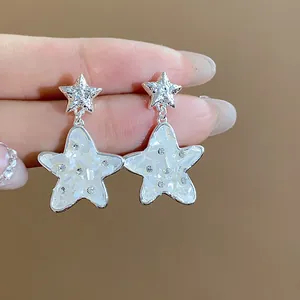 Primo piano dettagliato di orecchini a stella in argento con strass e decoro in vetro bianco.