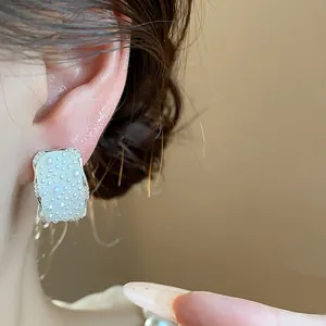 Dettaglio di orecchini rettangolari in stile coreano con perle bianche su modella