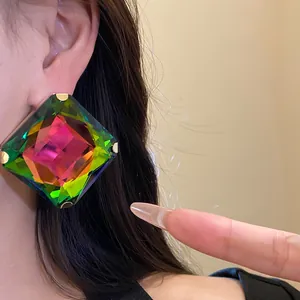 Close-up of a large iridescent square crystal earring on ear showing vibrant colors.