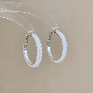 Close-up view of elegant silver hoop earrings adorned with small white pearls