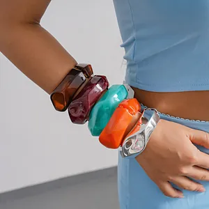 Detailed view of colorful irregular geometric resin and metallic bangles on a woman's wrist
