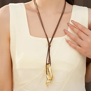 Dettaglio di una collana con ciondolo a conchiglia in metallo dorato e cordino marrone