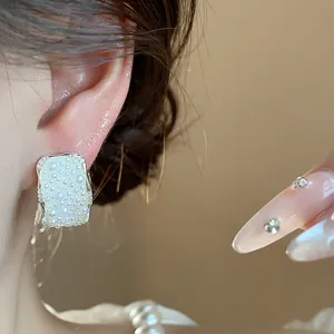 Primo piano di elegante orecchino a bottone rettangolare con perle e strass