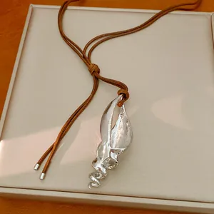 Vista dettagliata del pendente a conchiglia argento su una collana in corda marrone