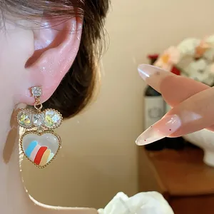 Gros plan de boucles d'oreilles cœur plaquées or 18 carats avec rayures arc-en-ciel et nœud