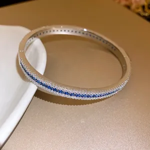Detailed macro view of a silver-toned zircon bangle with inlaid blue and white stones
