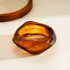 Detail showing the amber resin texture and irregular geometric shape of the hinged bangle.
