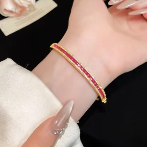 Close-up detail of a vintage gold-plated bangle set with red and clear zircon stones