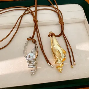 Vista dettagliata di ciondoli a forma di conchiglia in oro e argento con lacci in cuoio