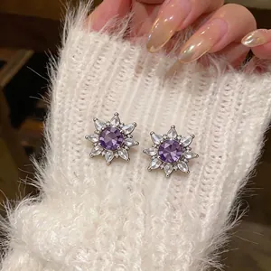 Elegant purple zircon flower ear clips on white fuzzy fabric texture